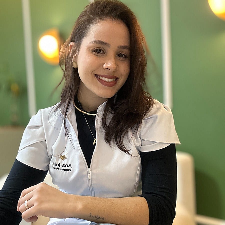 Ana Julia Pires, terapeuta manual, sorrindo em seu espaço de atendimento